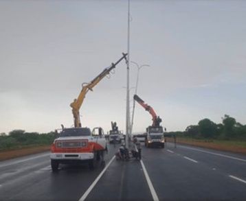 Grúas instalando postes de iluminación en una autopista